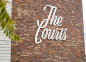 Thumbnail 19 of 31 - a brick wall with a white sign on it at The Courts Midtown, Memphis, TN, 38104
