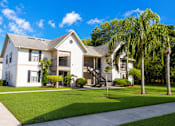 Thumbnail 22 of 26 - A white house with a grey roof and a green lawn in front.
