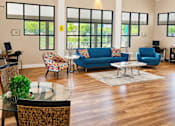 Thumbnail 2 of 26 - A living room with a blue couch and a glass table.