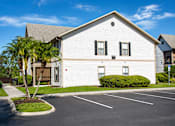 Thumbnail 26 of 26 - A white building with a grey roof and a parking lot in front.