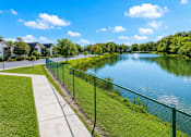 Thumbnail 10 of 26 - A serene lake surrounded by a green fence and a clear blue sky.