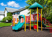 Thumbnail 6 of 26 - A playground with a green slide and red and yellow play structure.