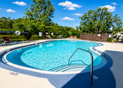 Thumbnail 5 of 26 - A blue swimming pool surrounded by a black fence and trees.