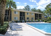 Thumbnail 1 of 3 - A pool area with chairs and a building in the background.