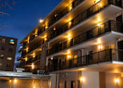 Thumbnail 3 of 6 - A building with balconies lit up at night.