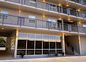 Thumbnail 5 of 6 - A large building with a lot of windows and lights on the balcony.