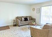 Thumbnail 5 of 17 - A living room with a couch, a coffee table, and a clock on the wall.