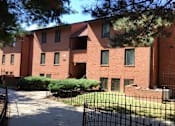 Thumbnail 7 of 21 - A red brick building with a black fence in front.