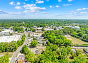 Thumbnail 4 of 9 - A bird's eye view of a town with a mix of greenery and buildings.