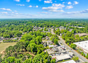 Thumbnail 3 of 9 - A bird's eye view of a small town with a mix of residential and commercial buildings surrounded by dense greenery.