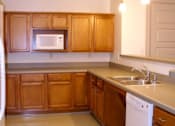 Thumbnail 3 of 4 - A kitchen with wooden cabinets and a white dishwasher.