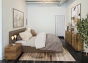 Thumbnail 8 of 16 - A bedroom with a bed, nightstand, and a plant.at South Main Artspace Lofts, Memphis Tennessee