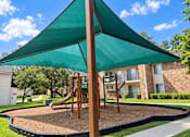 Thumbnail 6 of 33 - A playground with a green canopy and a slide.
