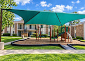 Thumbnail 4 of 33 - A playground with a green canopy and a slide.