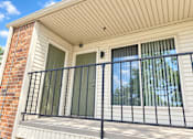 Thumbnail 7 of 33 - A balcony with a black railing and a window with a view of trees.