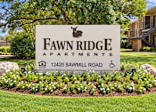 Thumbnail 3 of 33 - A sign for Fawn Ridge Apartments is surrounded by flowers.