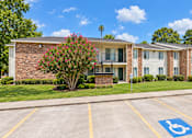 Thumbnail 20 of 33 - A parking lot with a handicap parking space in front of a brick building.