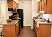 Thumbnail 21 of 33 - A kitchen with wooden cabinets and a black refrigerator.