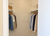 Thumbnail 33 of 33 - A white closet with clothes hanging on hangers.