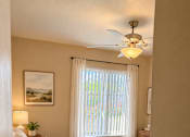 Thumbnail 25 of 33 - A bedroom with a bed, a ceiling fan, and a window with curtains.