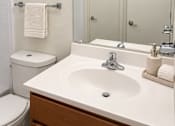 Thumbnail 28 of 33 - A white bathroom with a toilet, sink, and mirror.