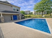 Thumbnail 5 of 21 - A residential house with a blue door and a pool in the backyard.