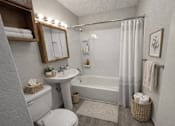Thumbnail 2 of 21 - A bathroom with a white toilet, sink, and bathtub.