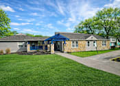 Thumbnail 11 of 21 - A house with a blue roof and a stone wall.