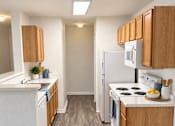 Thumbnail 10 of 15 - A kitchen with white appliances and wooden cabinets.