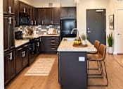 Thumbnail 18 of 43 - A modern kitchen with dark wood cabinets and black appliances.