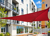 Thumbnail 32 of 43 - A red canopy is over a table and chairs outside a building.