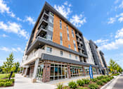 Thumbnail 16 of 43 - A modern multi-story building with a glass entrance and a brick base.