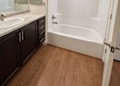 Thumbnail 40 of 43 - A white bathroom with a white tub and a white sink.