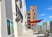 Thumbnail 43 of 43 - A long concrete walkway leads to a building with a red awning.