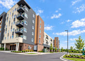 Thumbnail 42 of 43 - A modern apartment building with a parking lot in front.