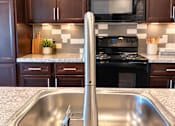 Thumbnail 27 of 43 - A kitchen with a stove, sink, and cabinets.