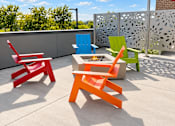 Thumbnail 38 of 43 - Four colorful chairs are arranged on a patio.