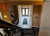 Thumbnail 43 of 43 - A hallway with a black railing and a black and white mat on the floor.