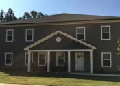 Thumbnail 3 of 13 - a brown house with white pillars and a white door