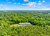 Thumbnail 6 of 10 - A bird's eye view of a large green forest with a few buildings in the distance.
