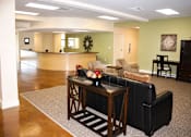 Thumbnail 5 of 7 - A living room with a black leather couch and a wooden coffee table.