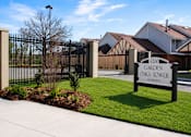 Thumbnail 2 of 7 - A sign for Garden Oaks Tower is in front of a black gate.
