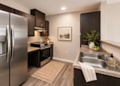 Thumbnail 4 of 12 - A modern kitchen with a stainless steel refrigerator and dark wood cabinets.