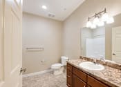Thumbnail 11 of 12 - A bathroom with a sink, toilet, and mirror.