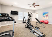 Thumbnail 5 of 12 - A home gym with a treadmill, exercise bike, and weights.