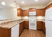 Thumbnail 8 of 12 - A kitchen with brown cabinets and white appliances.