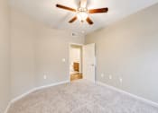 Thumbnail 10 of 12 - A room with a ceiling fan and carpeted floor.