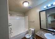 Thumbnail 14 of 15 - A white bathtub with a toilet and sink in a bathroom.