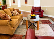 Thumbnail 1 of 19 - A living room with a yellow couch, a red chair, and a glass coffee table.