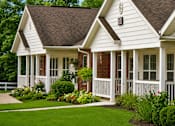 Thumbnail 3 of 19 - A white house with a brown roof and a porch.